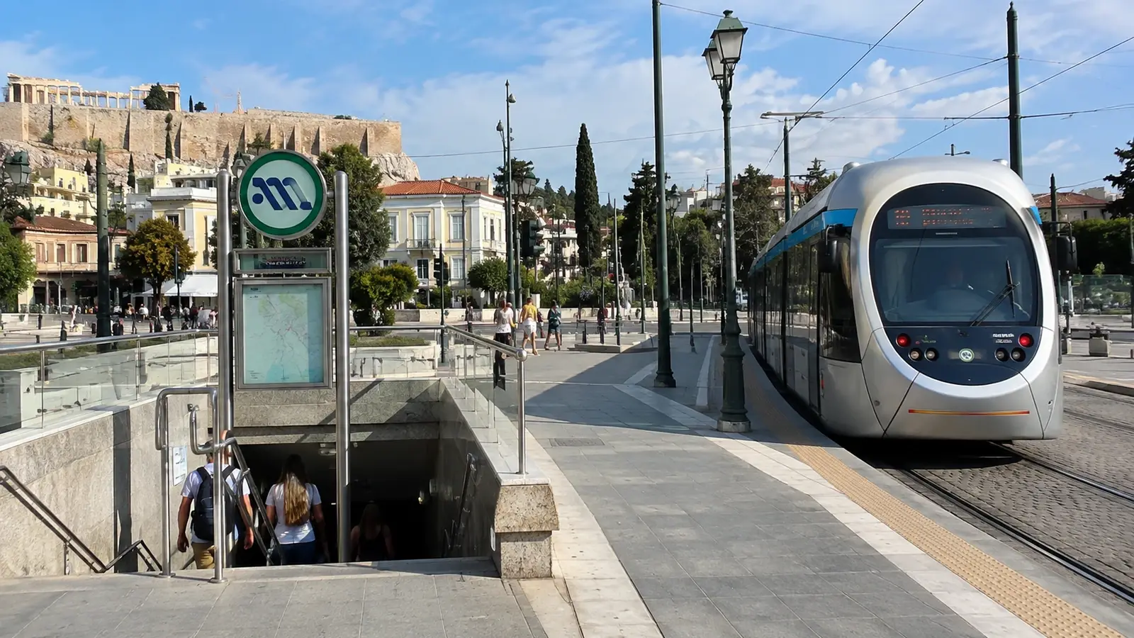 Spårvagn och metroentré i centrala Aten med Akropolis i bakgrunden